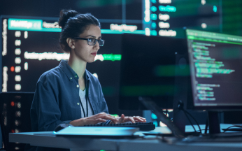 Woman working on a computer with digital screens in view